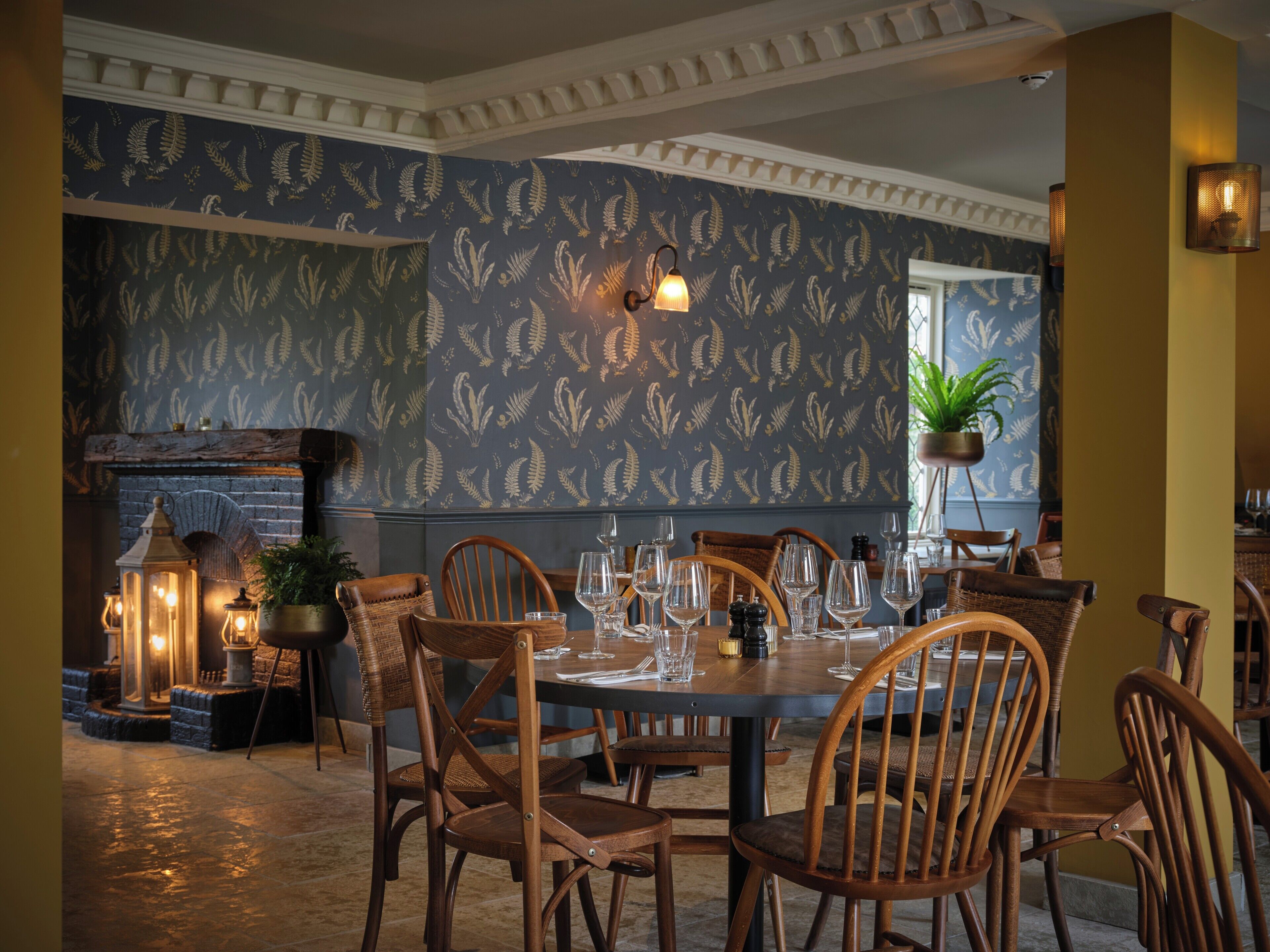 A dining area with a round table set for six, surrounded by wooden chairs.