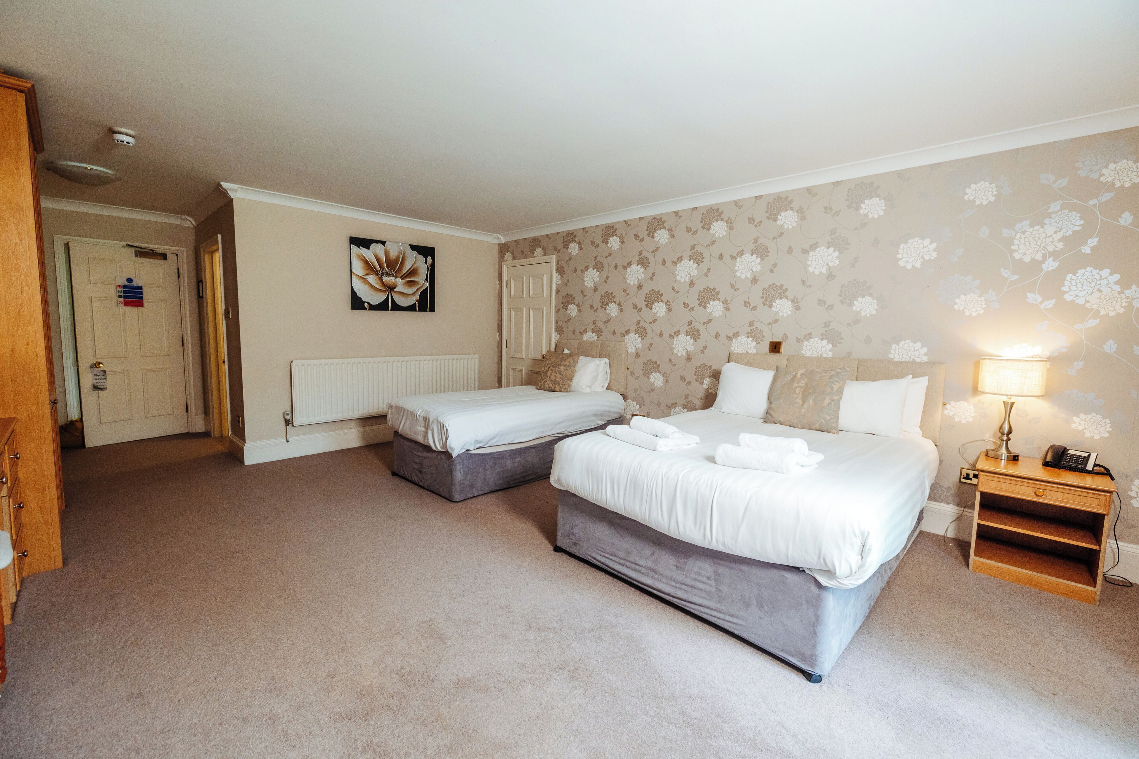 A bedroom with two single beds, a bedside table with a lamp, and a radiator.