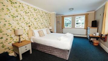 A neatly arranged bedroom with a bed, bedside table, lamp, and a window with curtains.