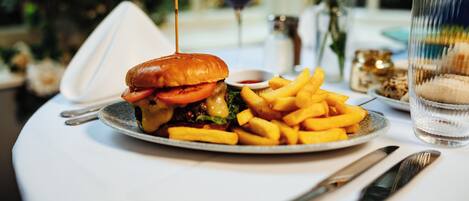 A plate with a burger and fries, a glass of wine, and a glass of water on a table.
