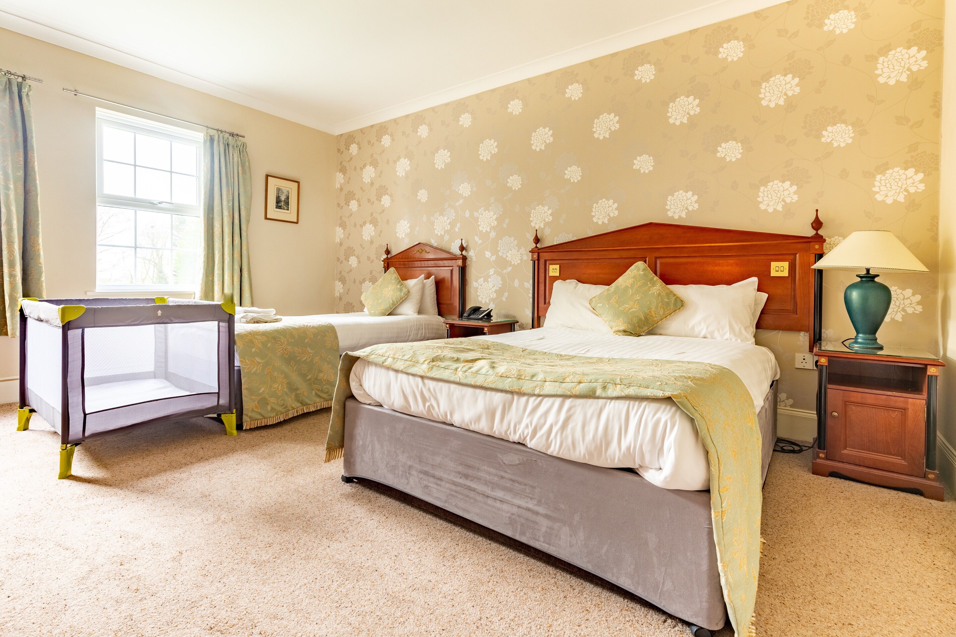 A hotel room with two beds, a desk, and a nightstand.