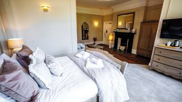 A hotel room with a bed, a television, a fireplace, and a mirror.
