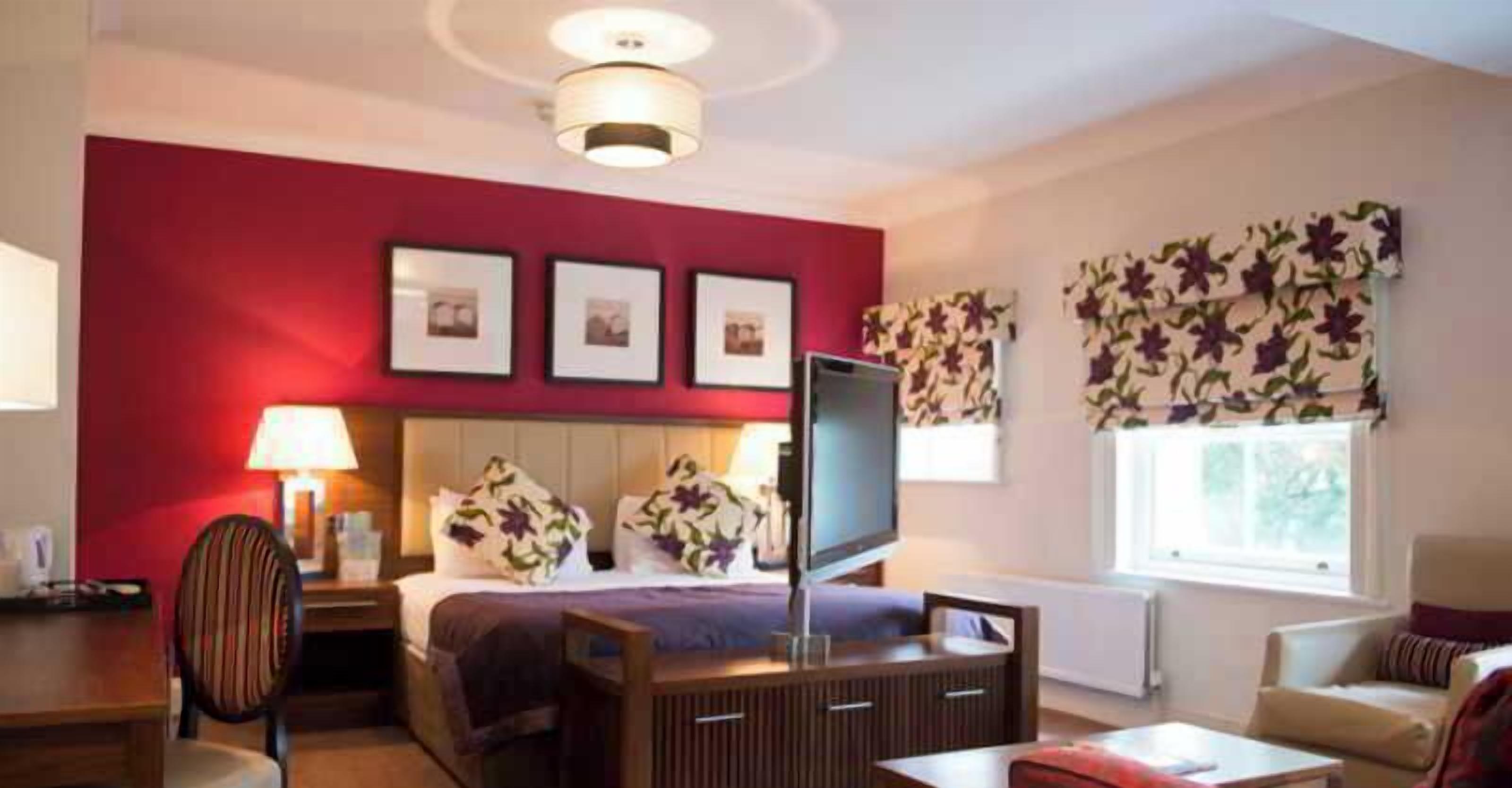 A hotel room with a bed, a TV, a desk, and a chair.
