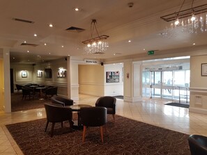 Un hall de hotel con una mesa redonda y sillas, una araña y un letrero que indica la Suite Brontë.