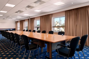 A conference room with a long table, black chairs, and large windows with curtains. - The Bradford Hotel (Bradford)
