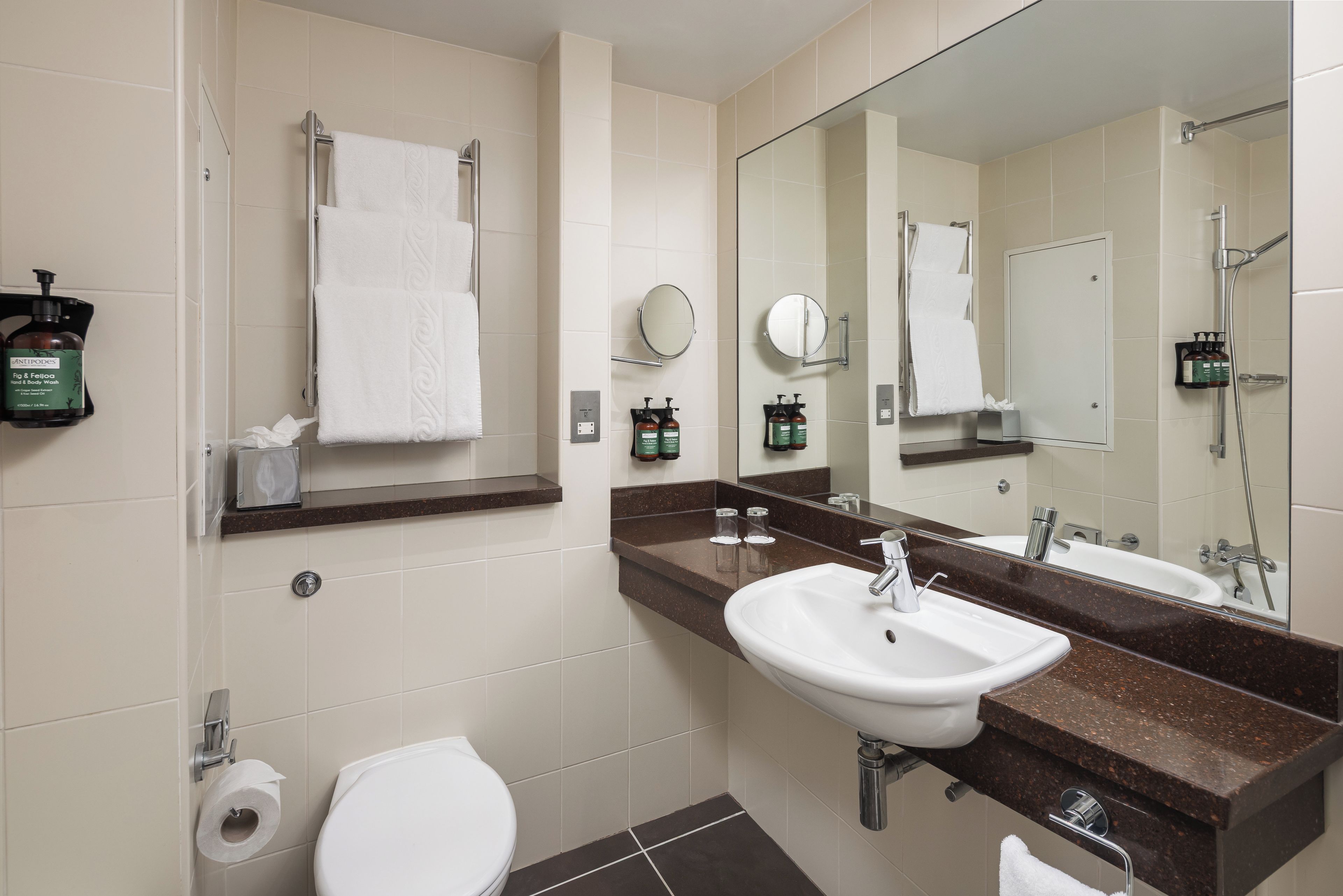 A modern bathroom with a white sink, a toilet, and a shower area.