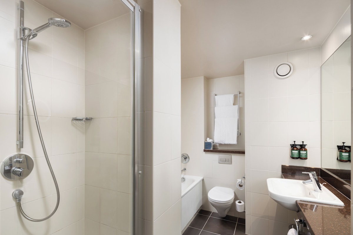 Ein modernes Badezimmer mit einer Duschkabine, einem weißen Waschbecken und einer Toilette.