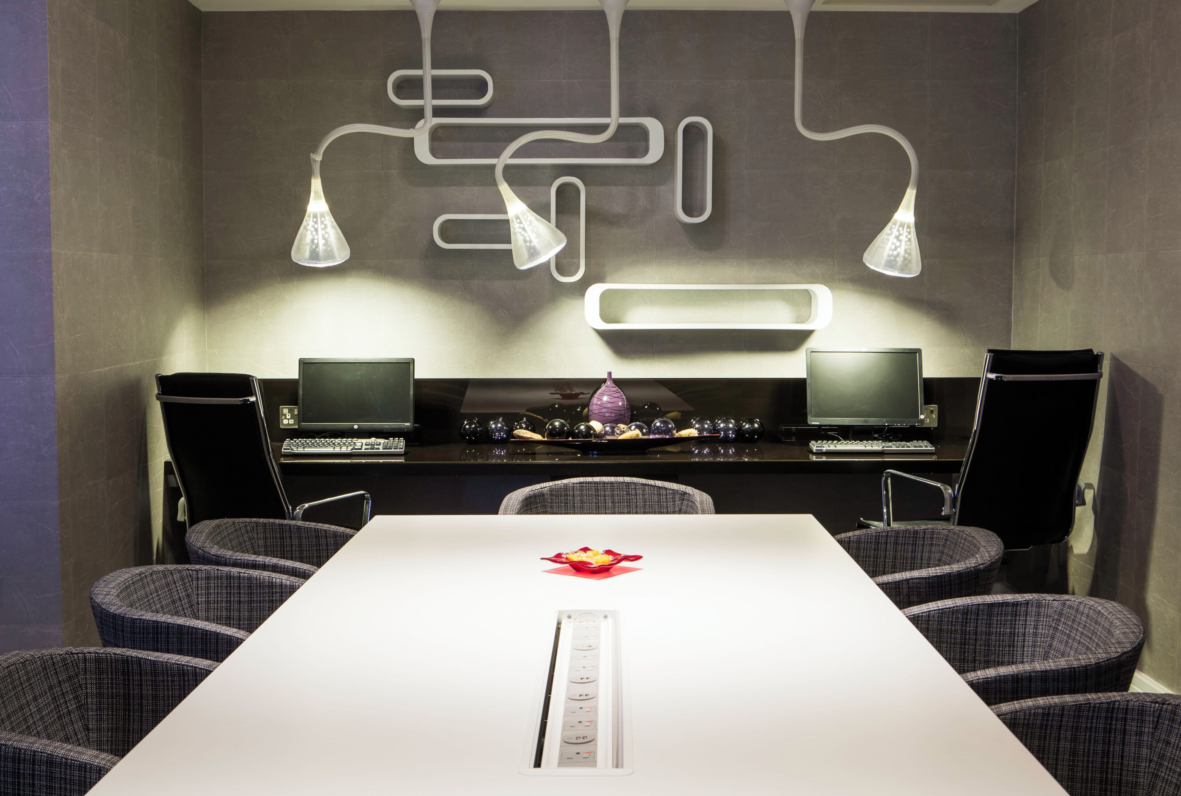 A conference room with a white table, two monitors, a keyboard, and two chairs.