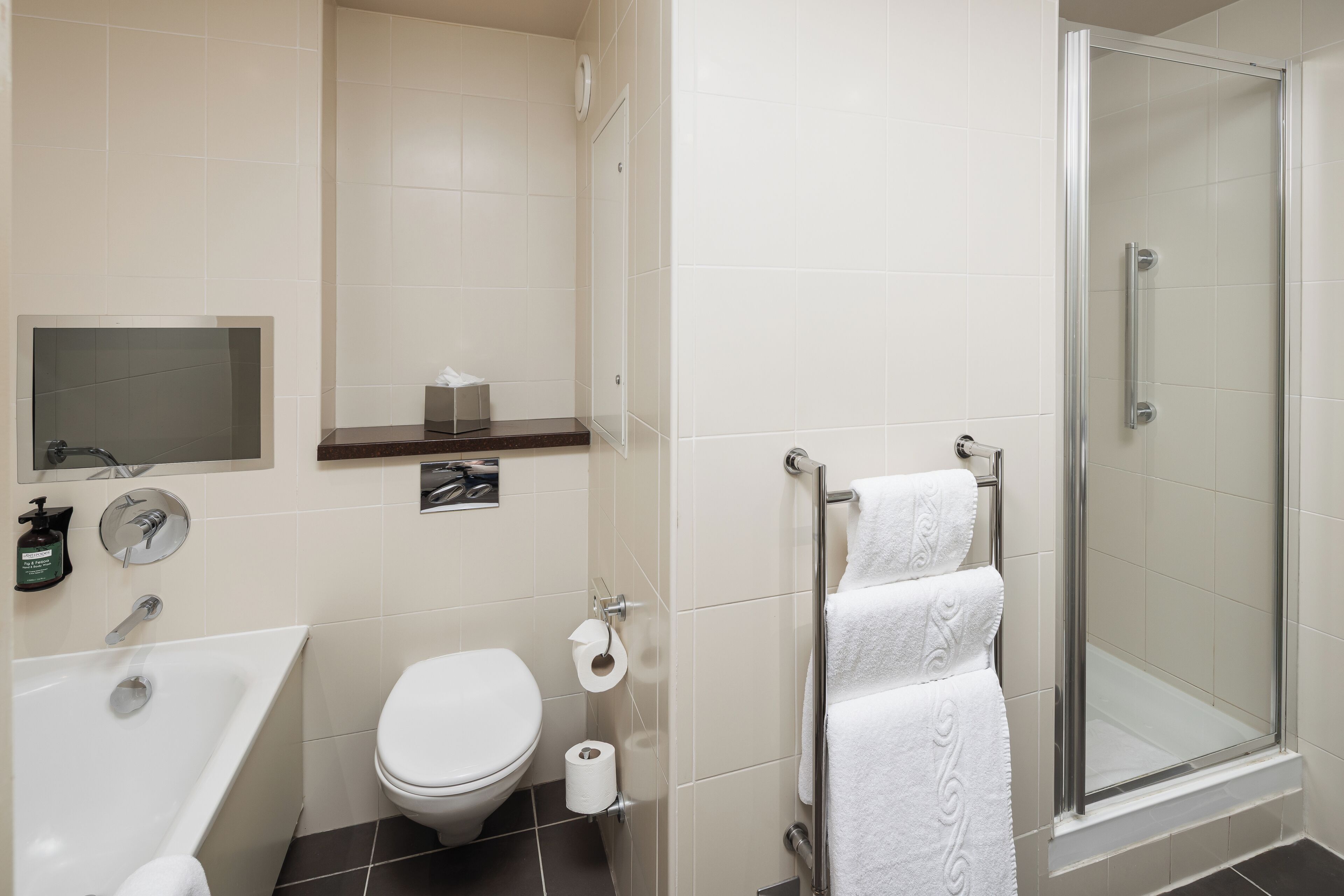 A modern bathroom with a bathtub, toilet, and glass-enclosed shower stall.