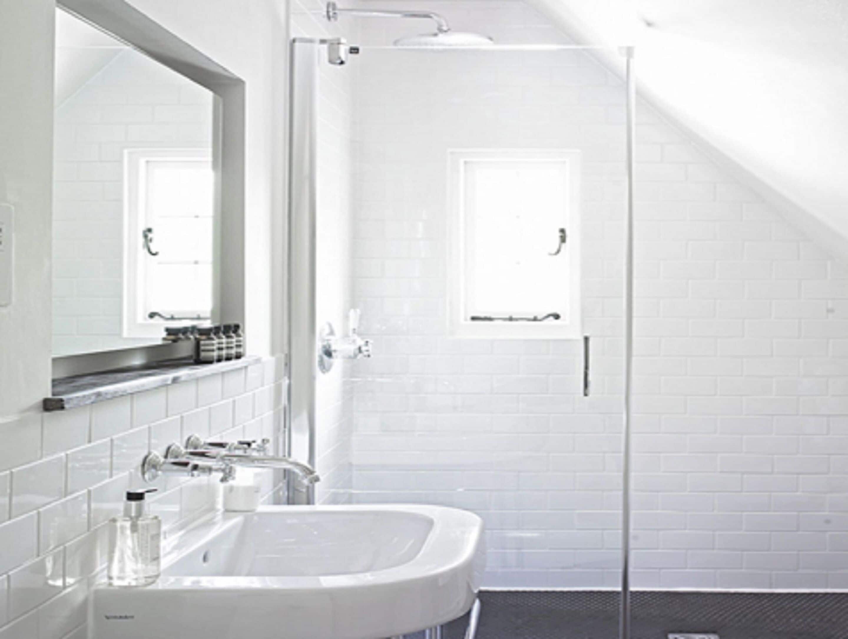 A modern bathroom with a white sink, mirror, and shower.