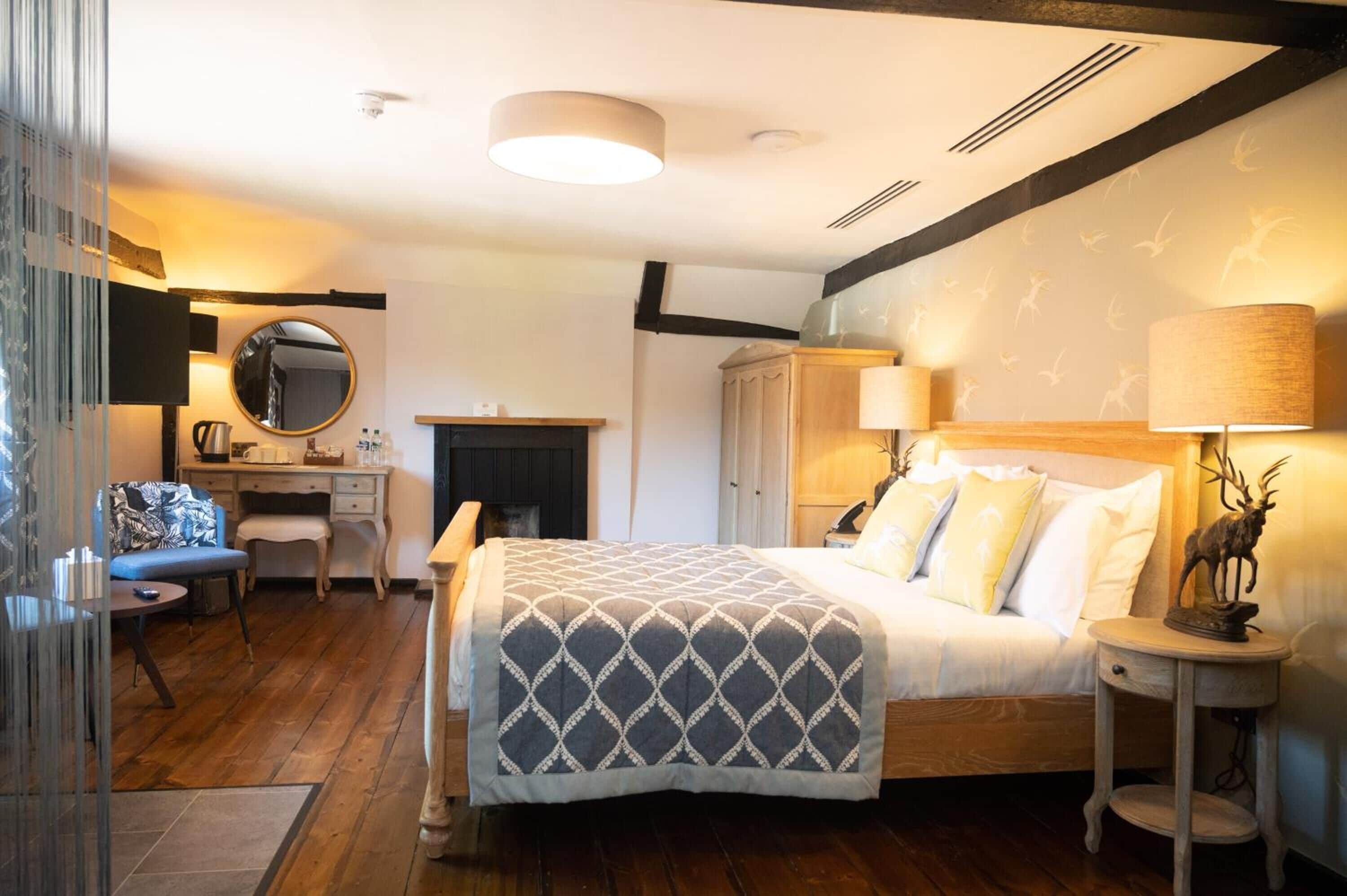 A bedroom with a bed, bedside table, lamp, and a mirror.