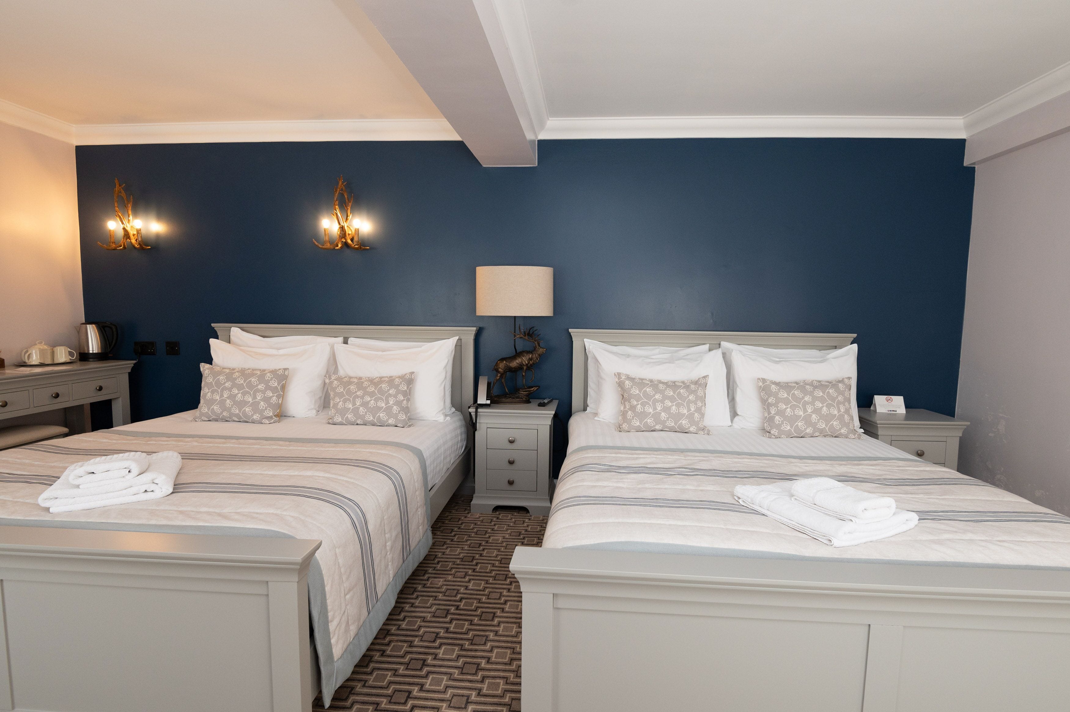 A hotel room with two beds, a nightstand with a lamp, and a decorative wall piece.