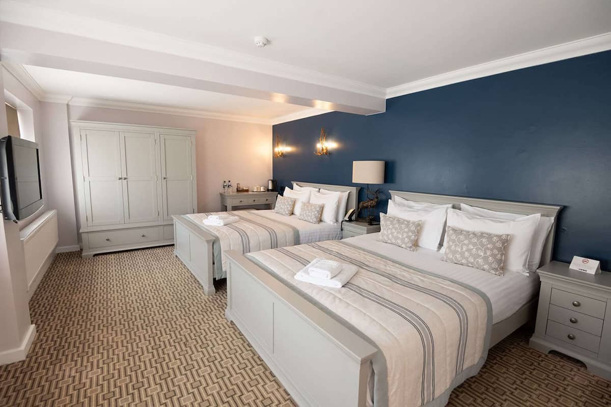 A hotel room with two beds, a wardrobe, a television, and a bathroom.