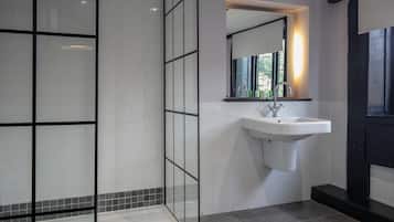 Un baño moderno con cabina de ducha de vidrio, un lavamanos blanco y un espejo encima.