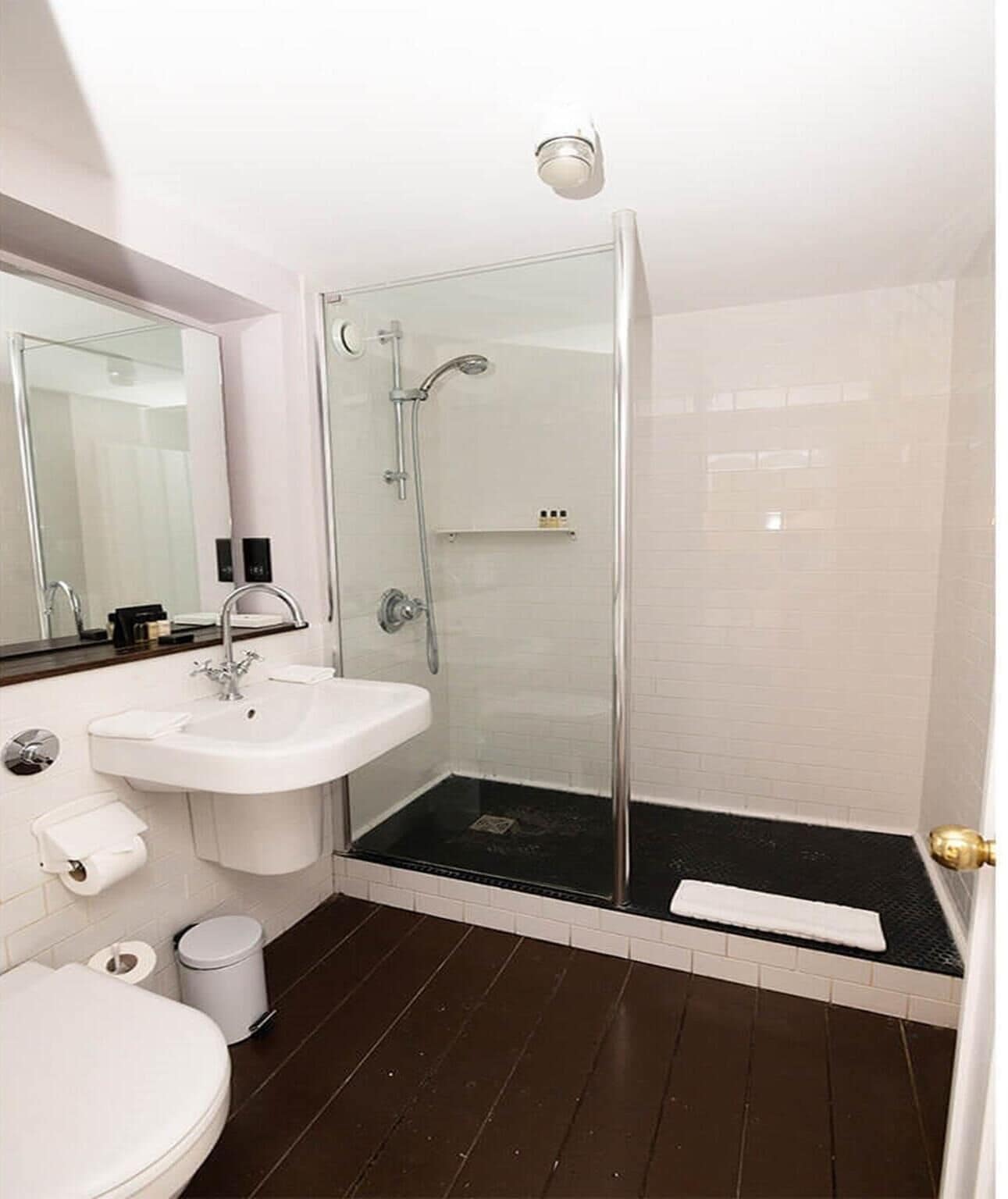 Uma casa de banho moderna com chuveiro envidraçado, lavatório branco e sanita.