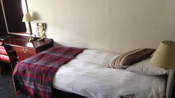 Una habitación de hotel con cama, escritorio, silla, lámpara y teléfono.