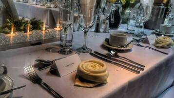 A table set for a formal dinner with a name card, cutlery, a folded napkin, and a small bowl of cream.