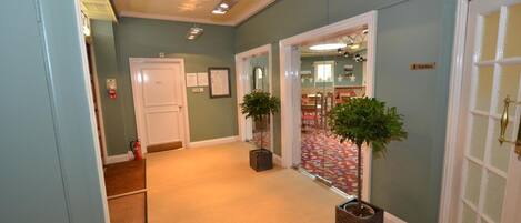 A hallway with a carpeted floor, a white door, and a sign indicating the ladies' room.