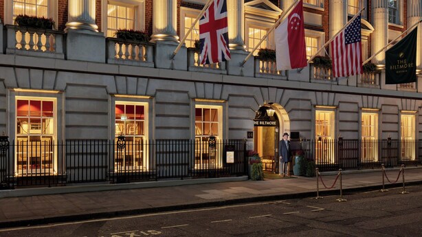 Fachada imponente de un hotel con amplias columnas, múltiples banderas y un estilo arquitectónico clásico.