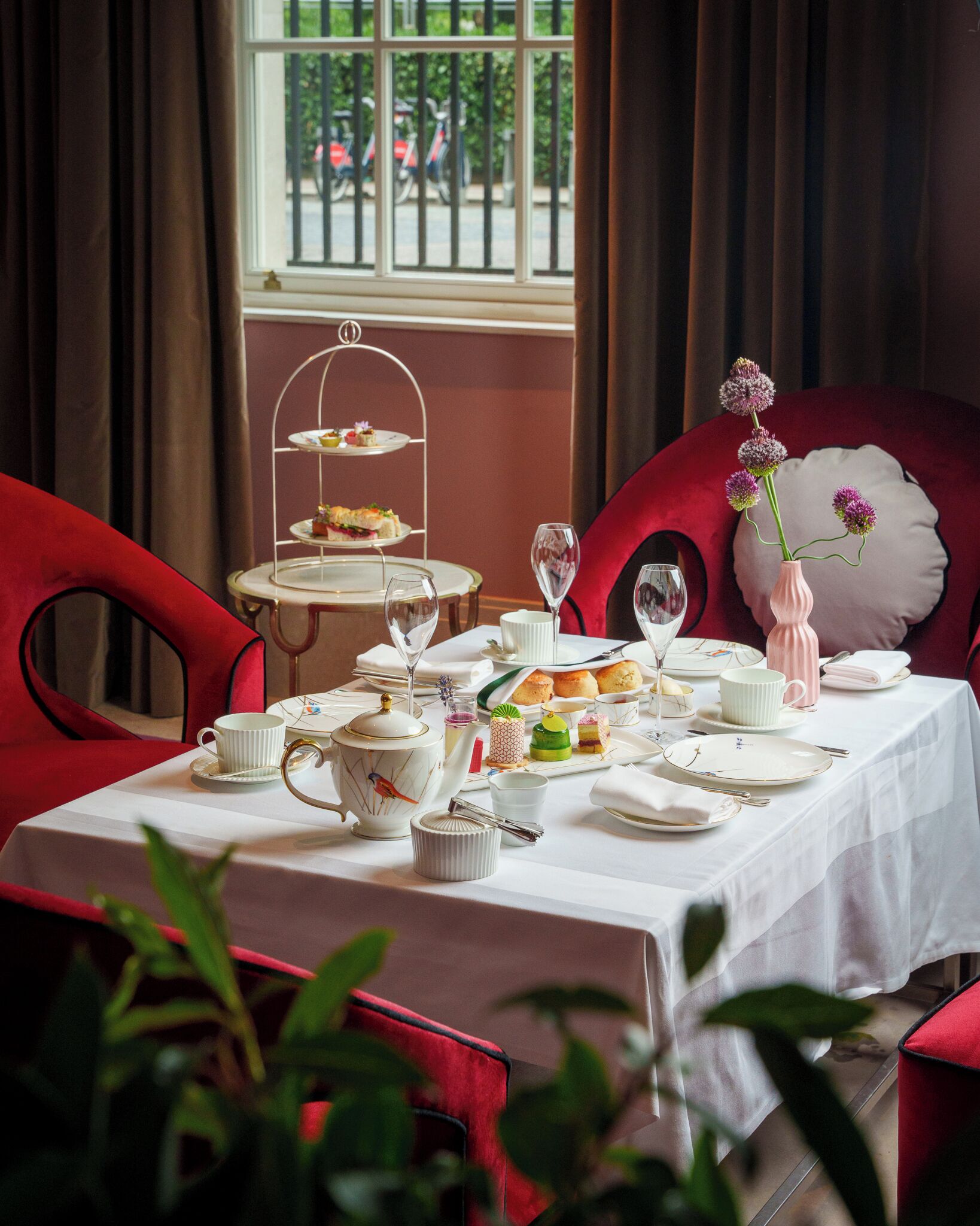 A dining table set with tea service, a dessert cart, and floral decorations.