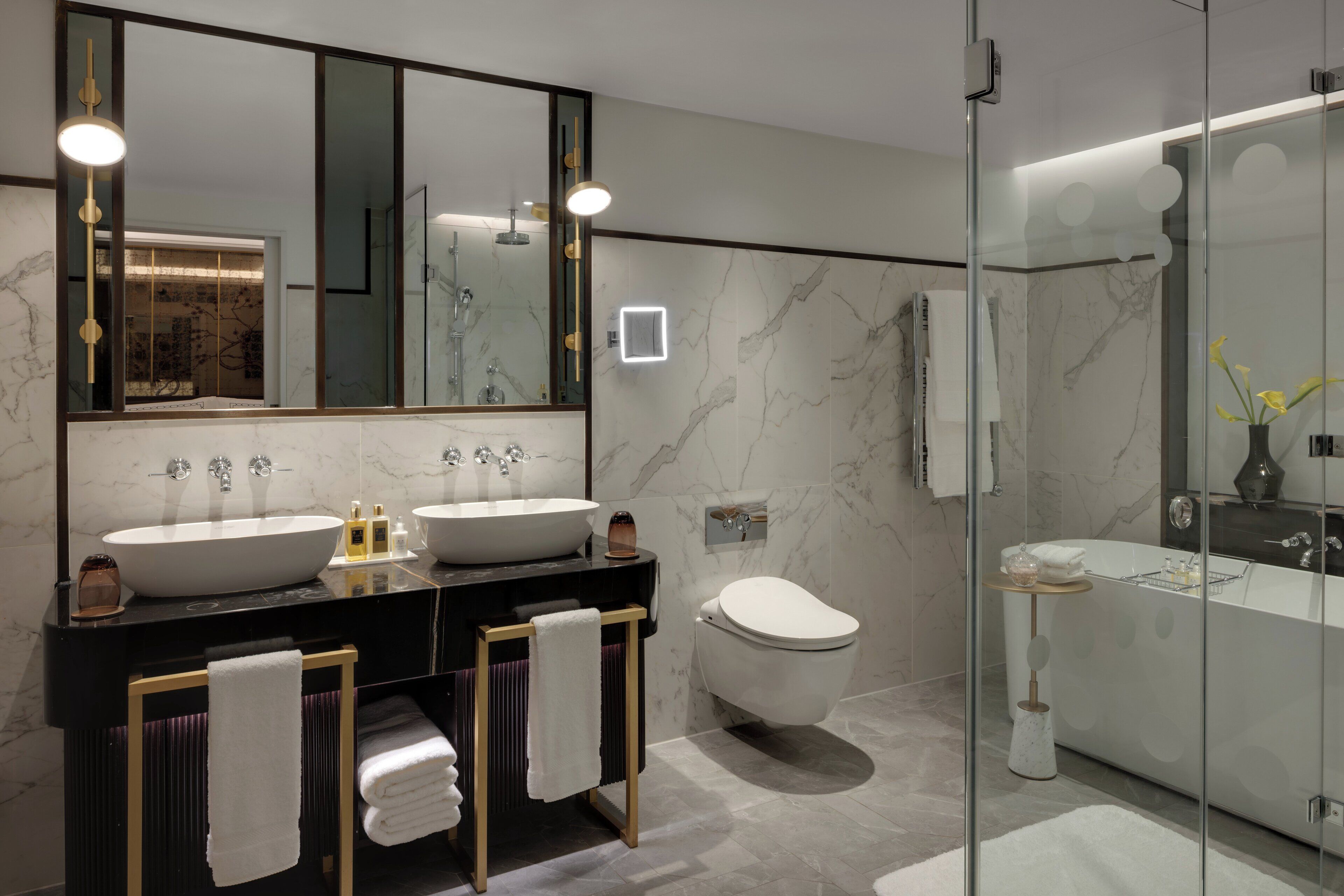 A modern bathroom with two sinks, a toilet, and a bathtub.