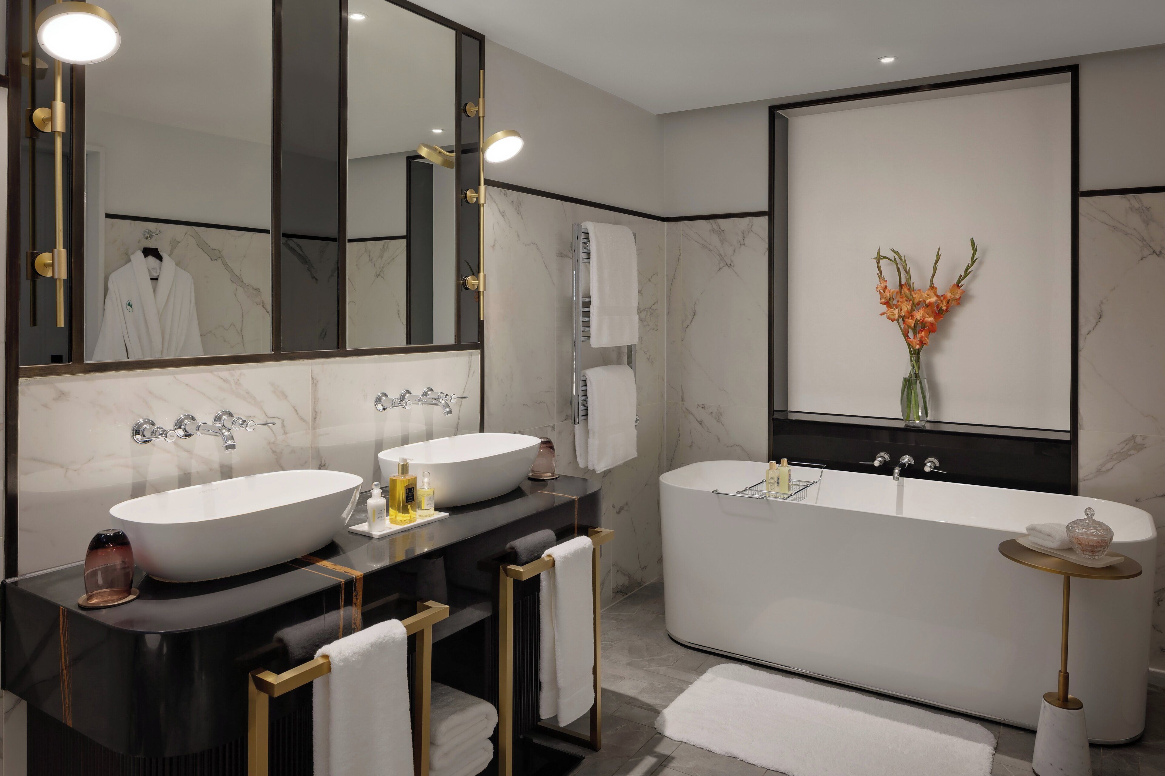 A modern bathroom with two sinks, a bathtub, and a large mirror.