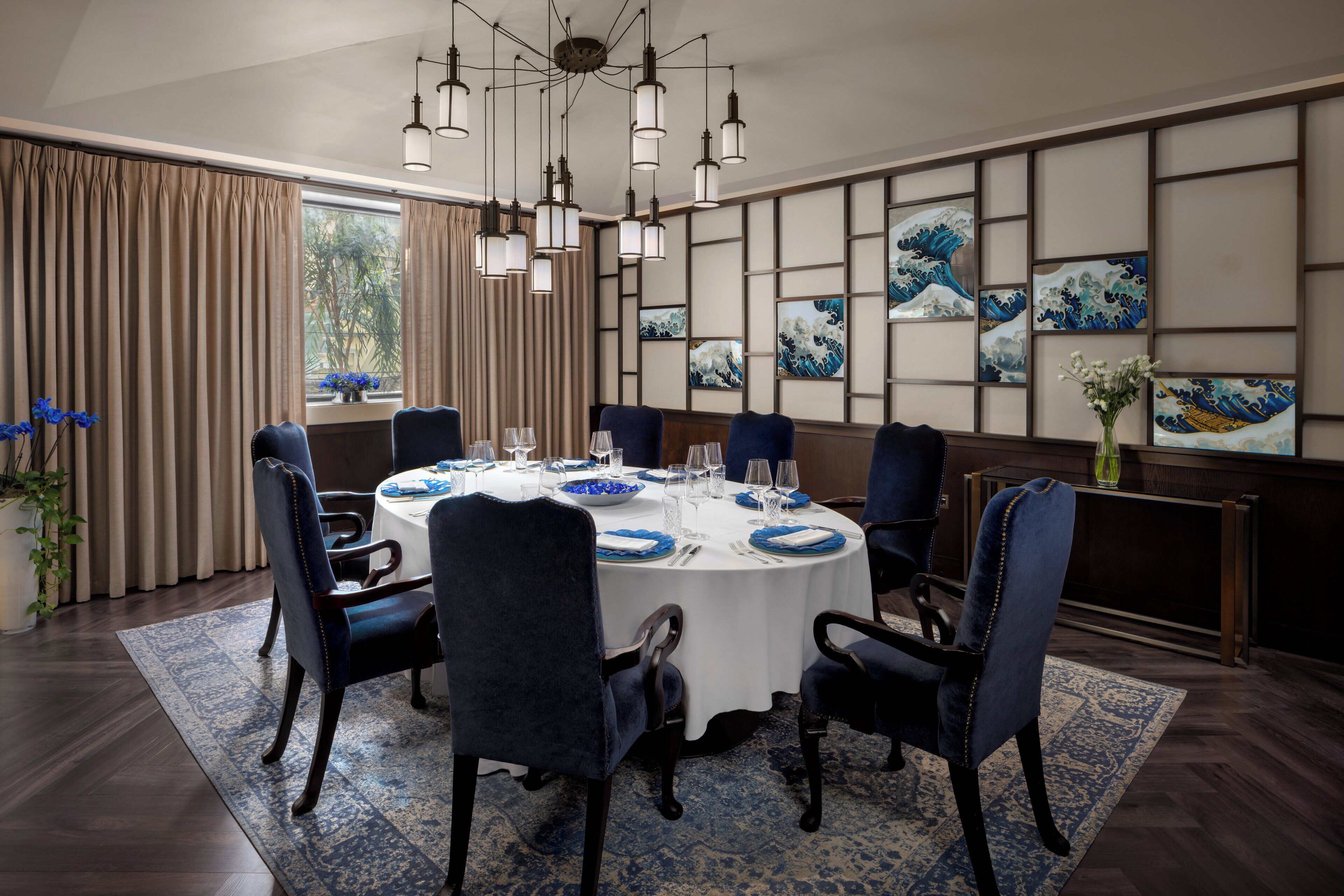 Comedor con una mesa redonda, sillas tapizadas en azul y mantel blanco.