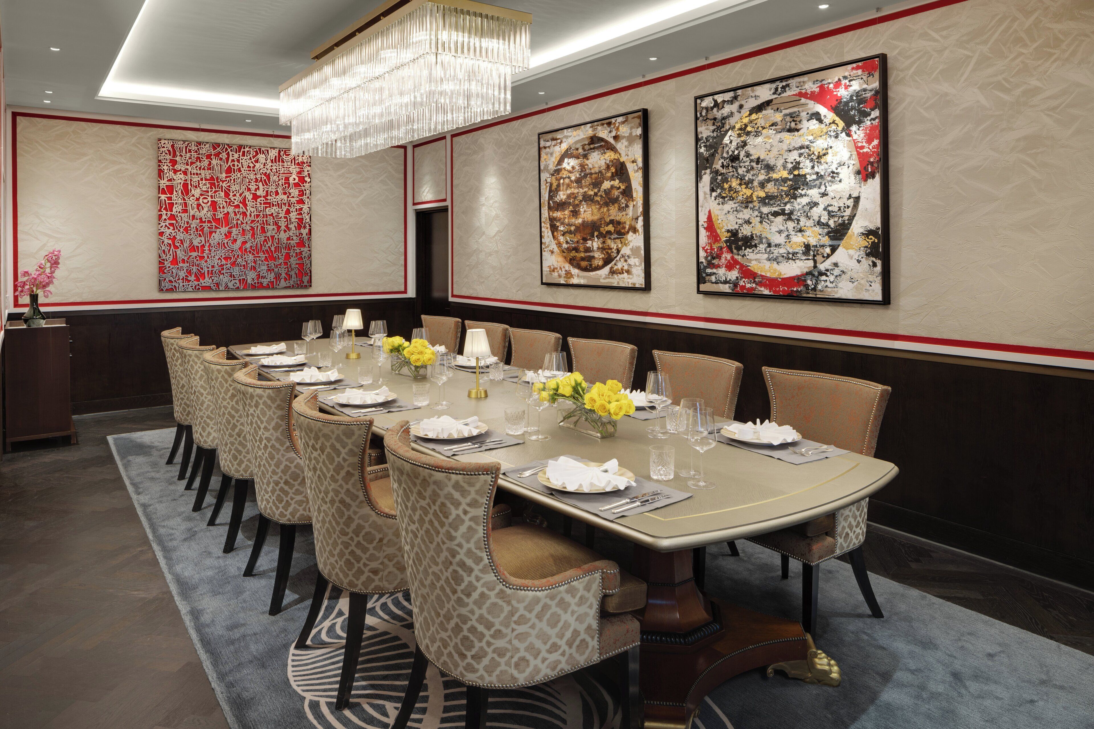 A formal dining room with a long table, multiple chairs, and a chandelier.