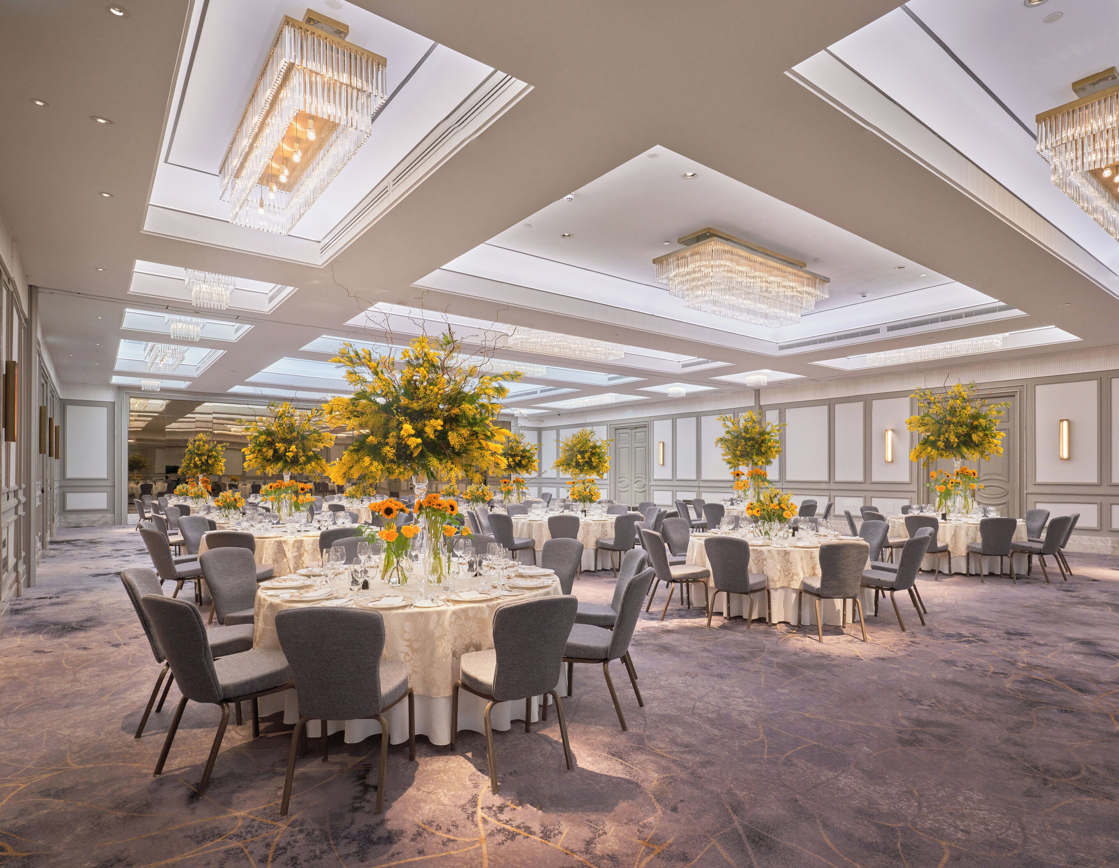 A spacious banquet hall with multiple round tables, each set with chairs and centerpieces.