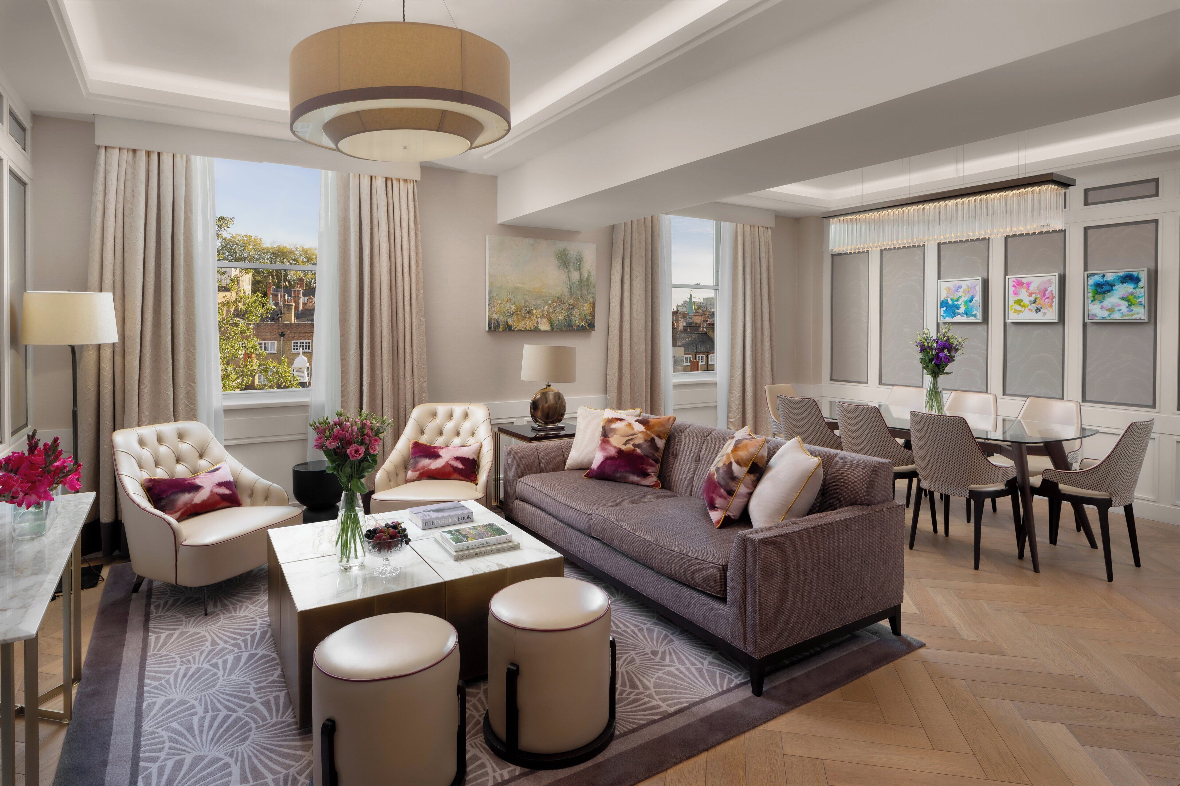 A modern living room with a sofa, armchairs, a coffee table, and a dining area with chairs and a table.