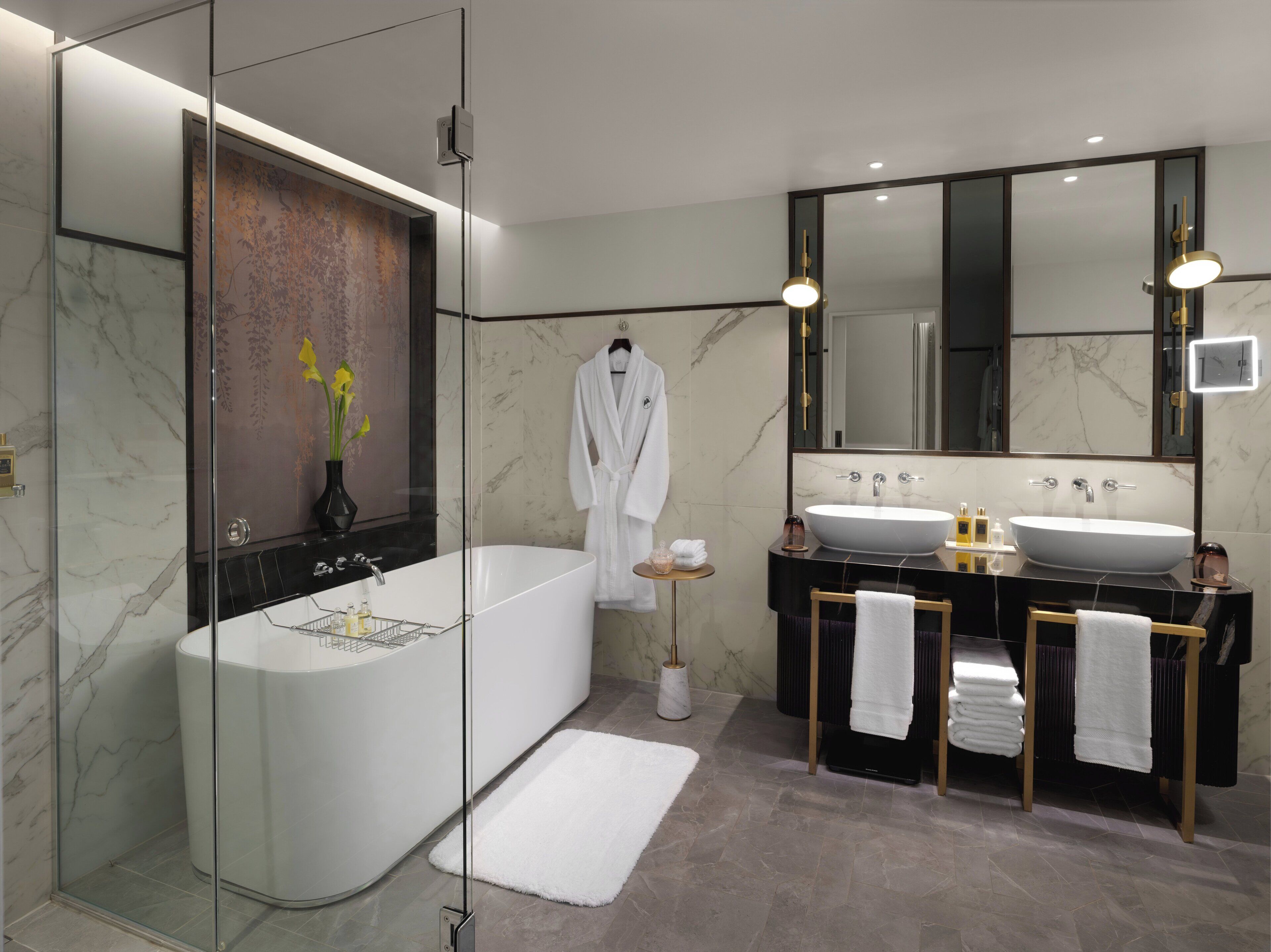 Un baño moderno con una bañera independiente, un espejo grande y un lavamanos doble.