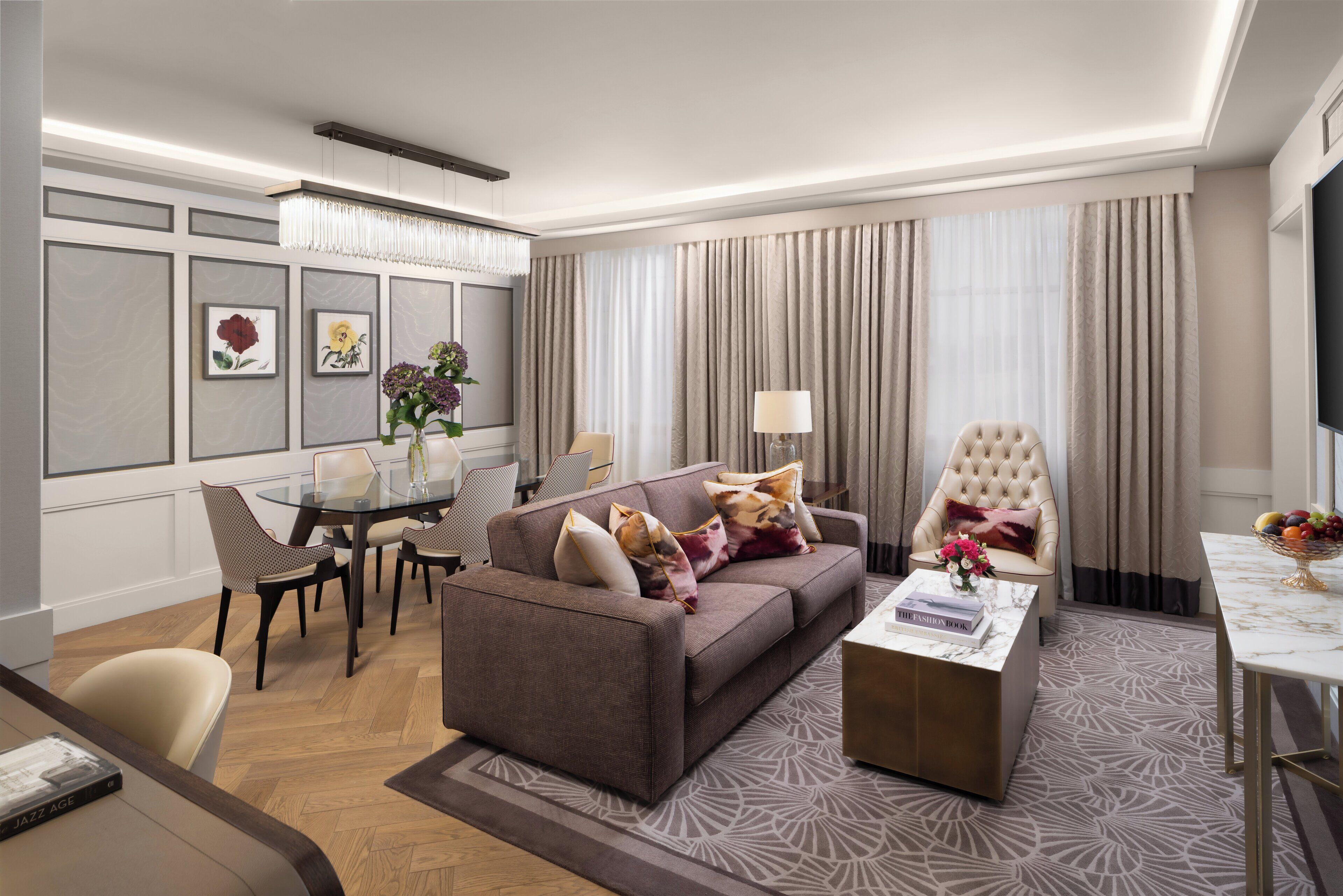 A modern living room with a sofa, armchairs, a coffee table, and a dining area with chairs and a glass table.