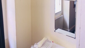 A room with a mounted television, a telephone, and a mirror on the wall. - Gresham Hotel Bloomsbury (London)