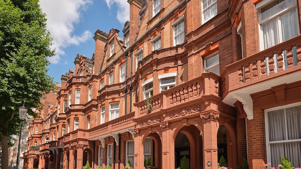 A row of red brick townhouses with arched windows and decorative brickwork.