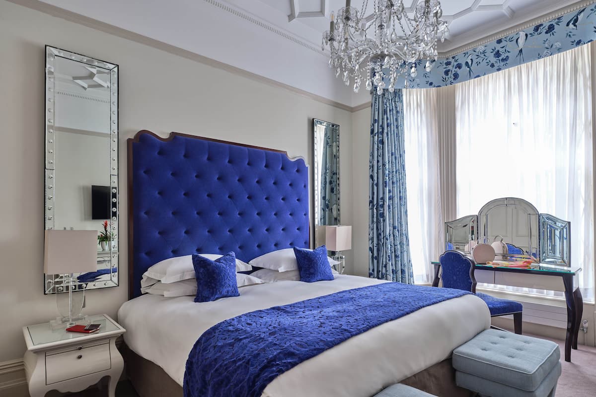 A bedroom with a large bed, a vanity with a mirror, and a chandelier.
