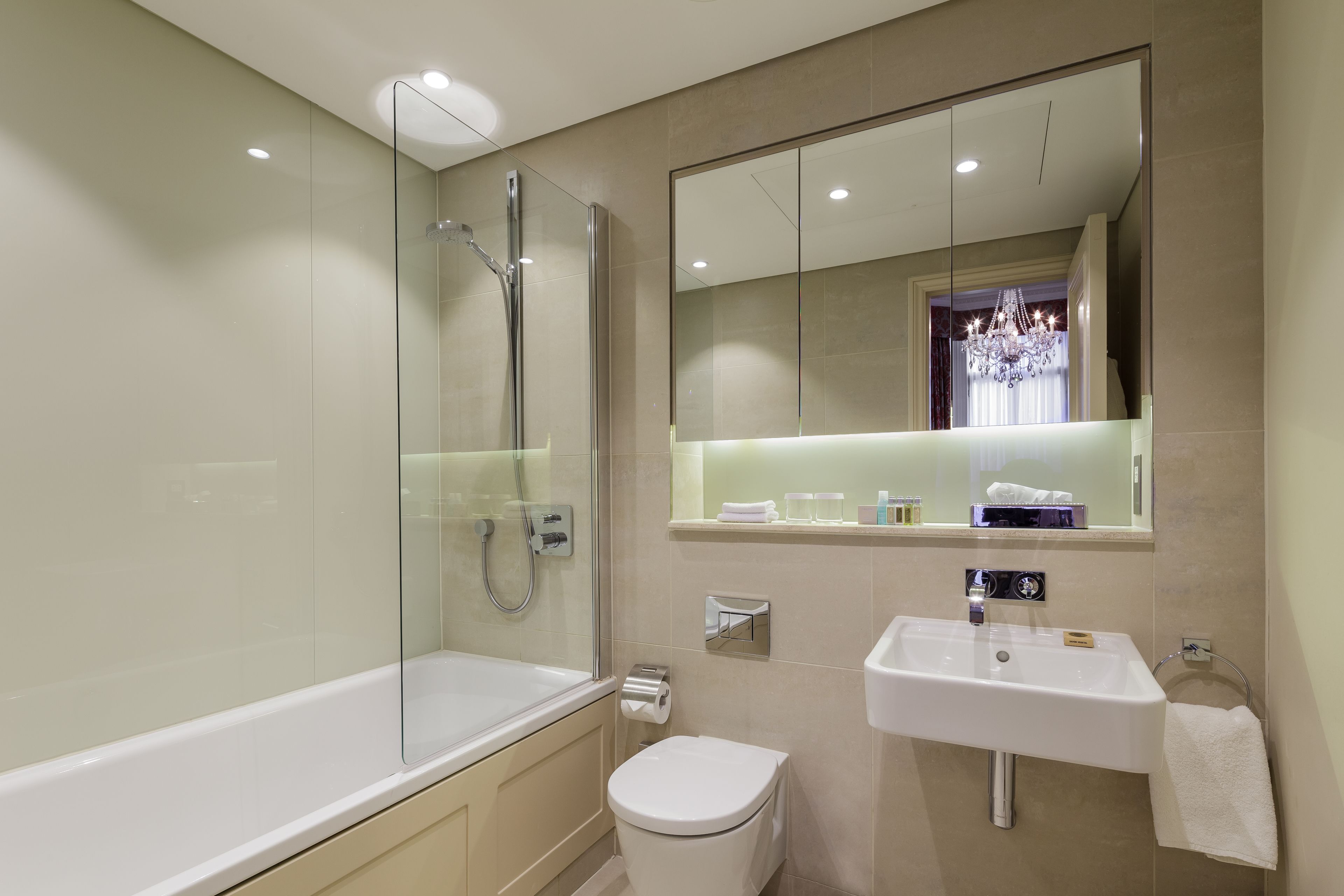 A modern bathroom with a glass-enclosed shower, a white toilet, a sink with a towel, and a mirror above the sink.