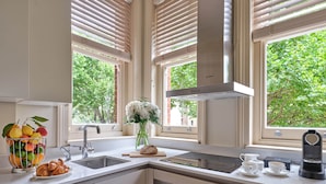 A modern kitchen with a built-in oven, a coffee maker, and a fruit bowl.