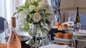 A dining table set with plates, glasses, a bottle of wine, and a floral centerpiece.