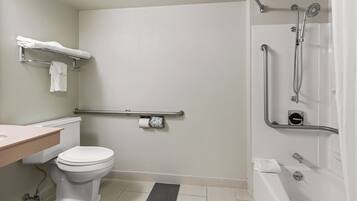 A bathroom with a toilet, sink, and bathtub. There is a grab bar next to the toilet and a showerhead above the bathtub.