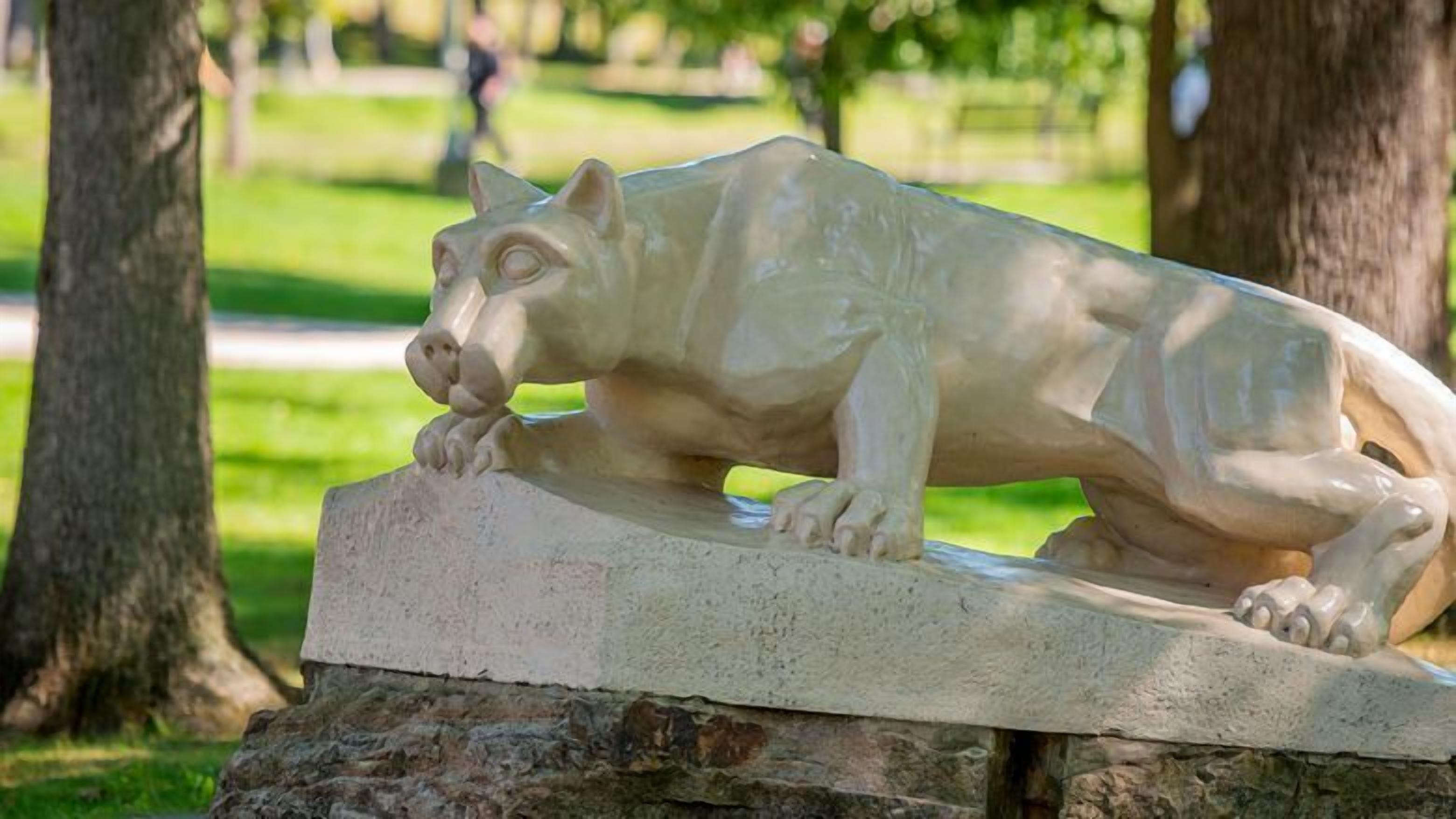 A stone sculpture of a dog in a park.