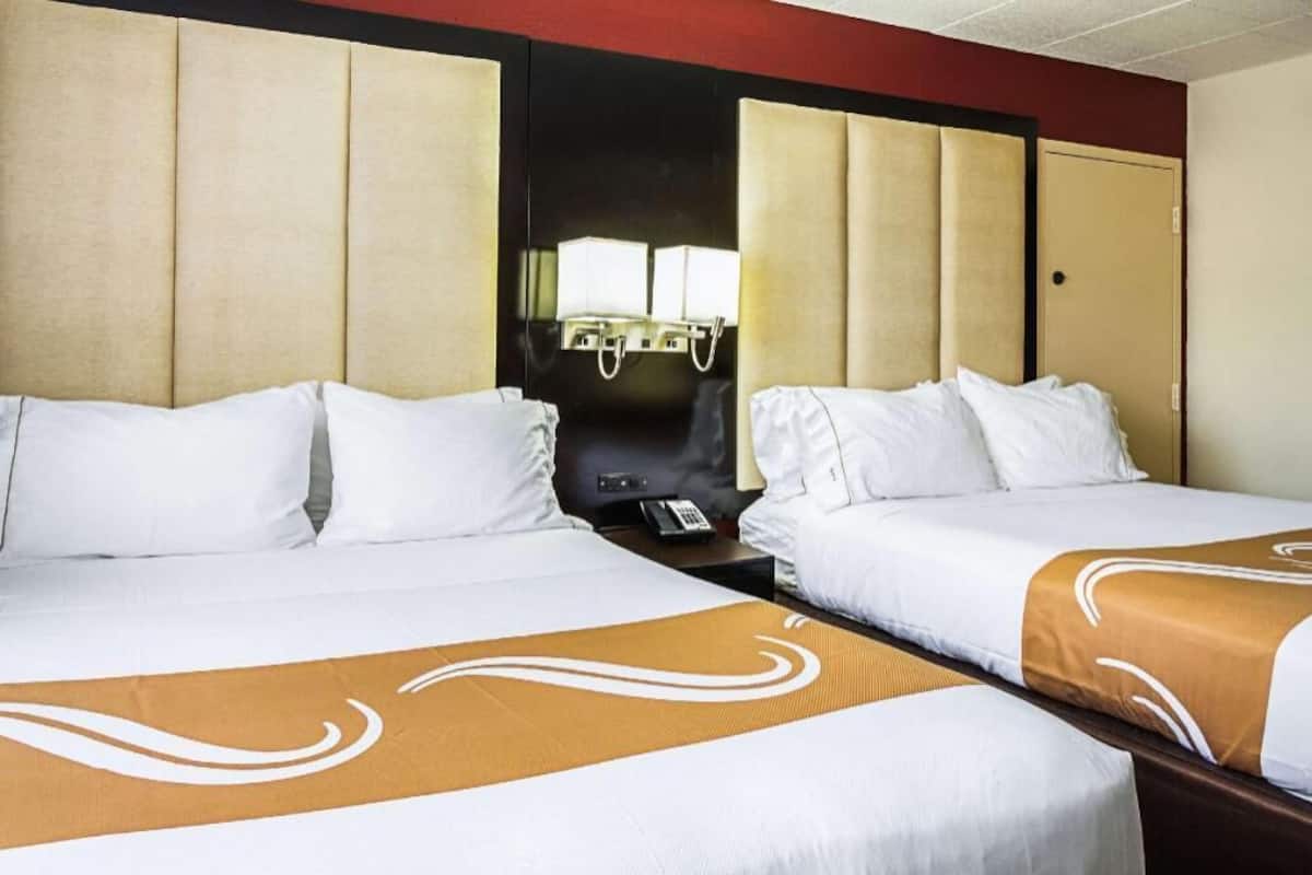 Ett hotellrum med två sängar, en minibar och en spegel.