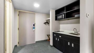 A compact kitchen with a built-in microwave, a sink, and cabinets.