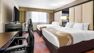 Una habitación de hotel con cama, escritorio, silla, televisor y ventana con cortinas.