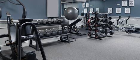 A gym with various exercise equipment including treadmills, kettlebells, and dumbbells.