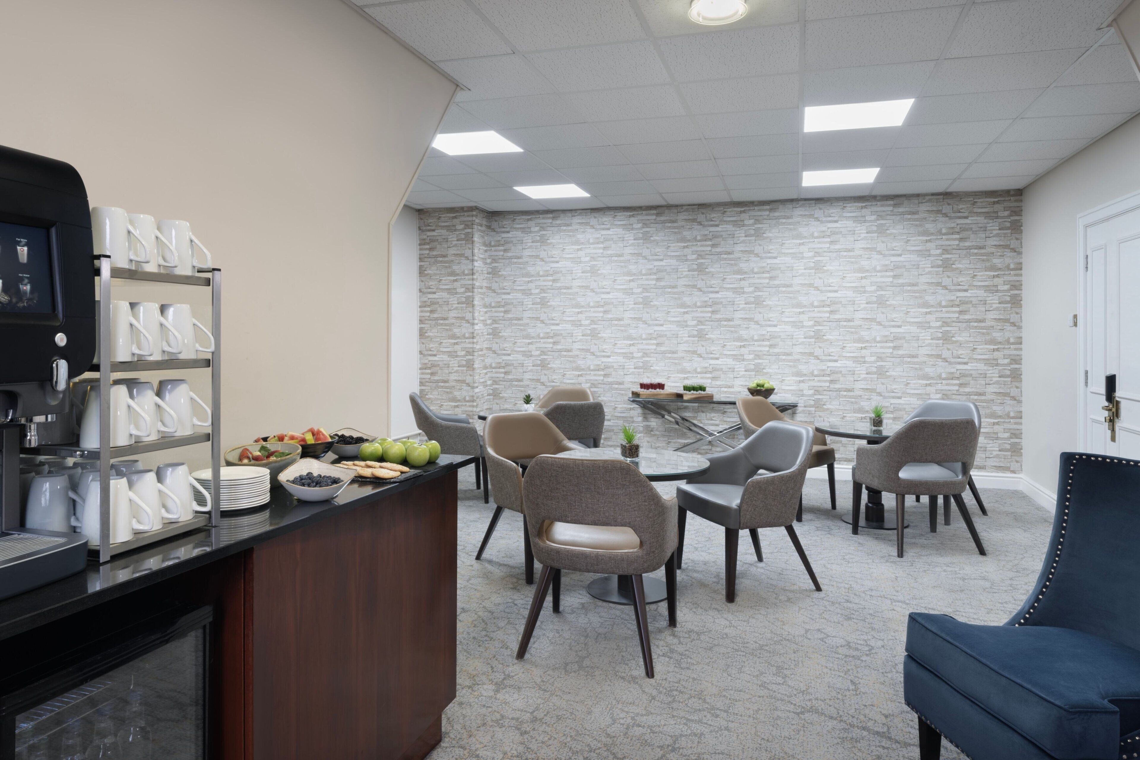 A modern conference room with a stone wall, a coffee station, and several chairs arranged around a table.