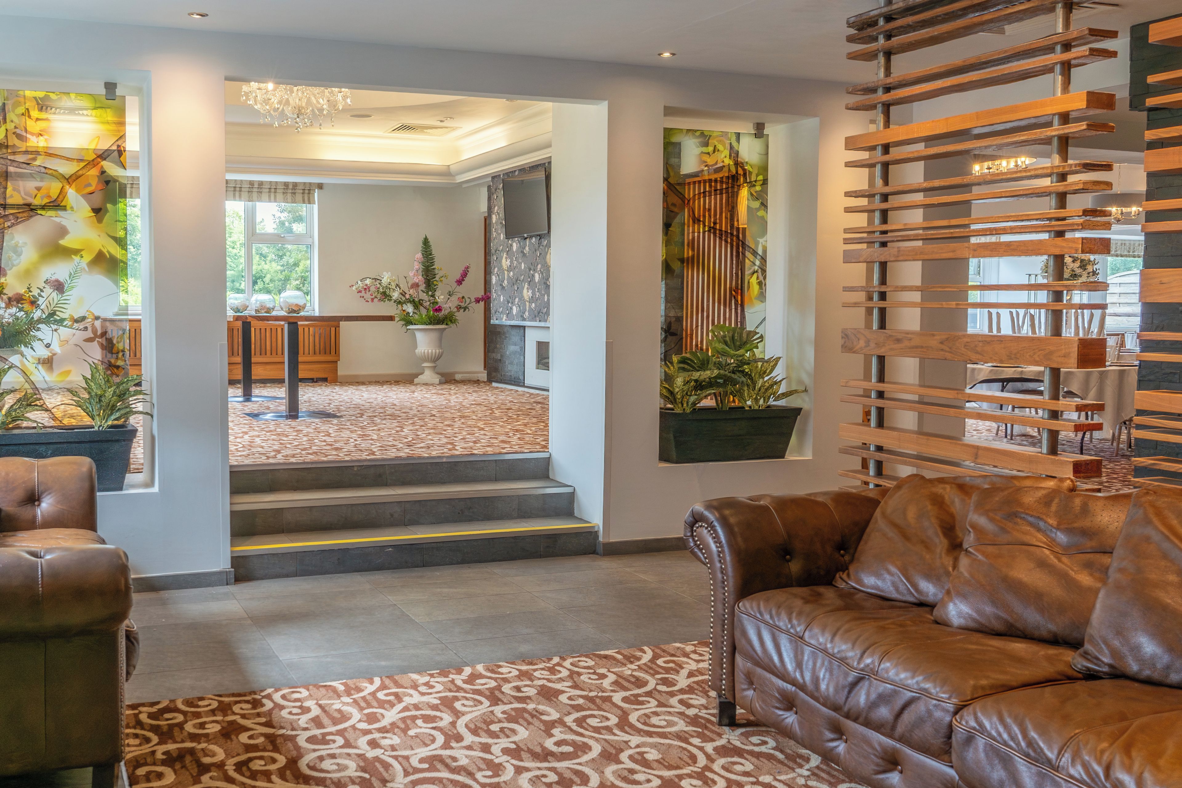 A spacious living area with a leather sofa, a patterned rug, and a large window with a view of a dining area.