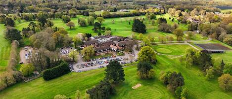 Egy golfpálya légi felvételén látható a klubház, a parkoló és a környező zöldterületek.