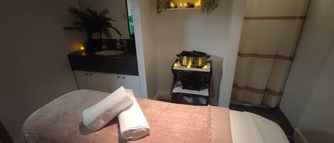 A hotel room with a bed, a bedside table, a mirror, a sink, and a small stove.