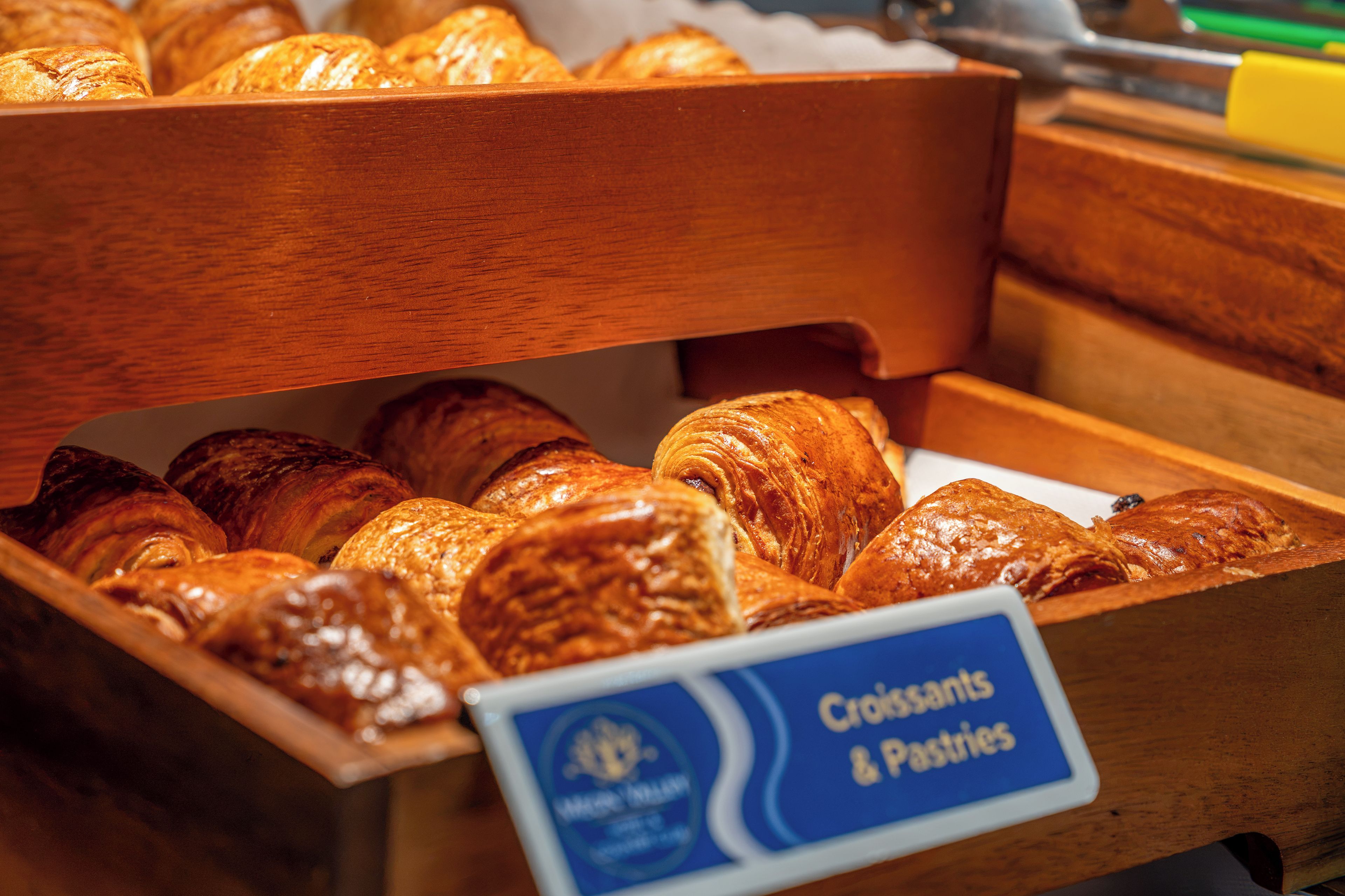 A wooden display case with a sign indicating it contains croissants and pastries.