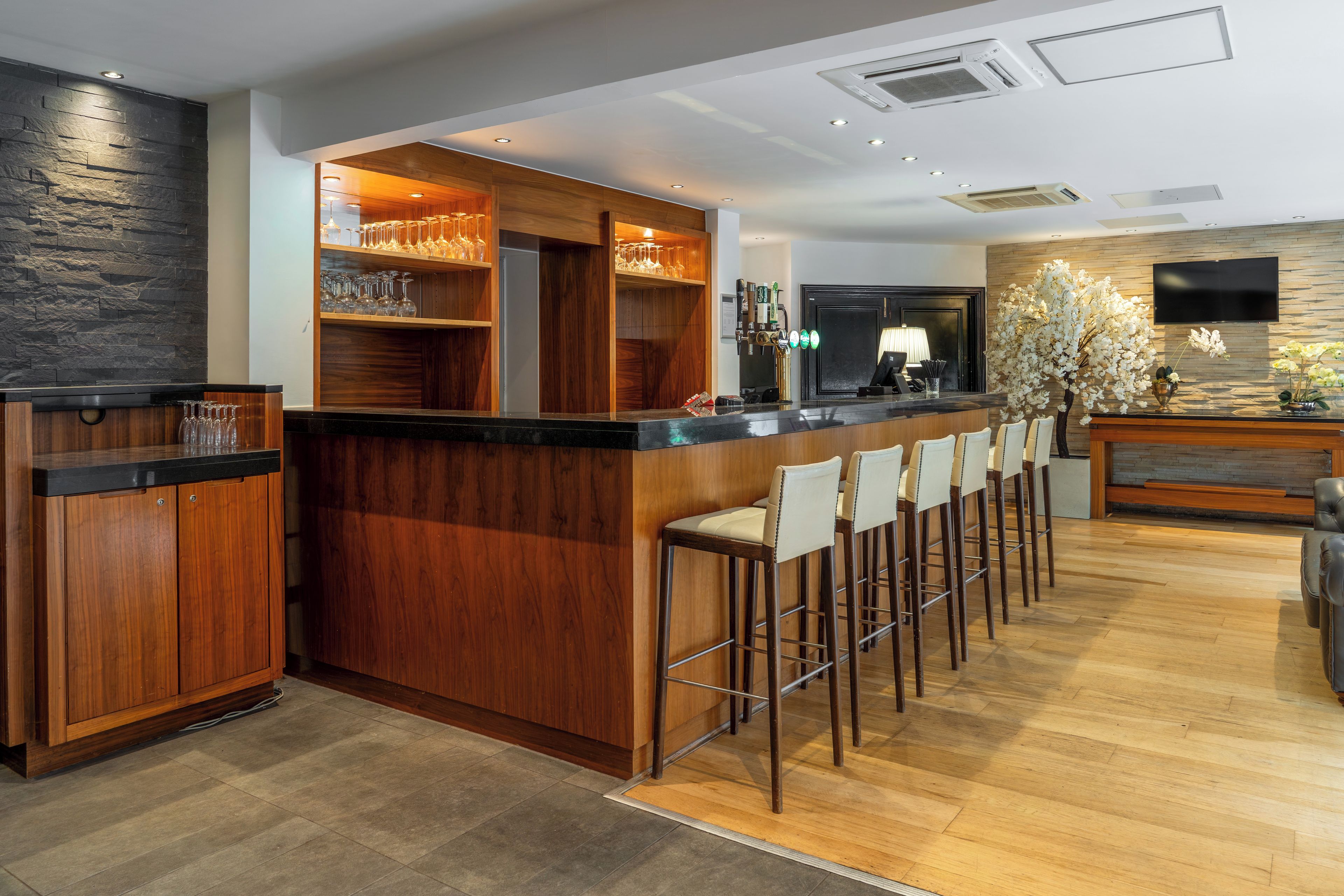 Una cocina moderna con barra de madera, taburetes y una estantería empotrada para vinos.